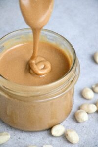 almond butter being poured into a glass jar