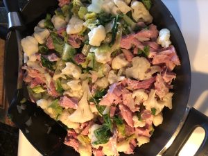 chunks of ham, cauliflower, spinach and greens for ham casserole in frying pan