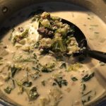 creamy sausage and greens soup in silver pot with large black spoon