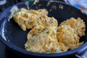scrambled eggs with dill and chicken in frying pan